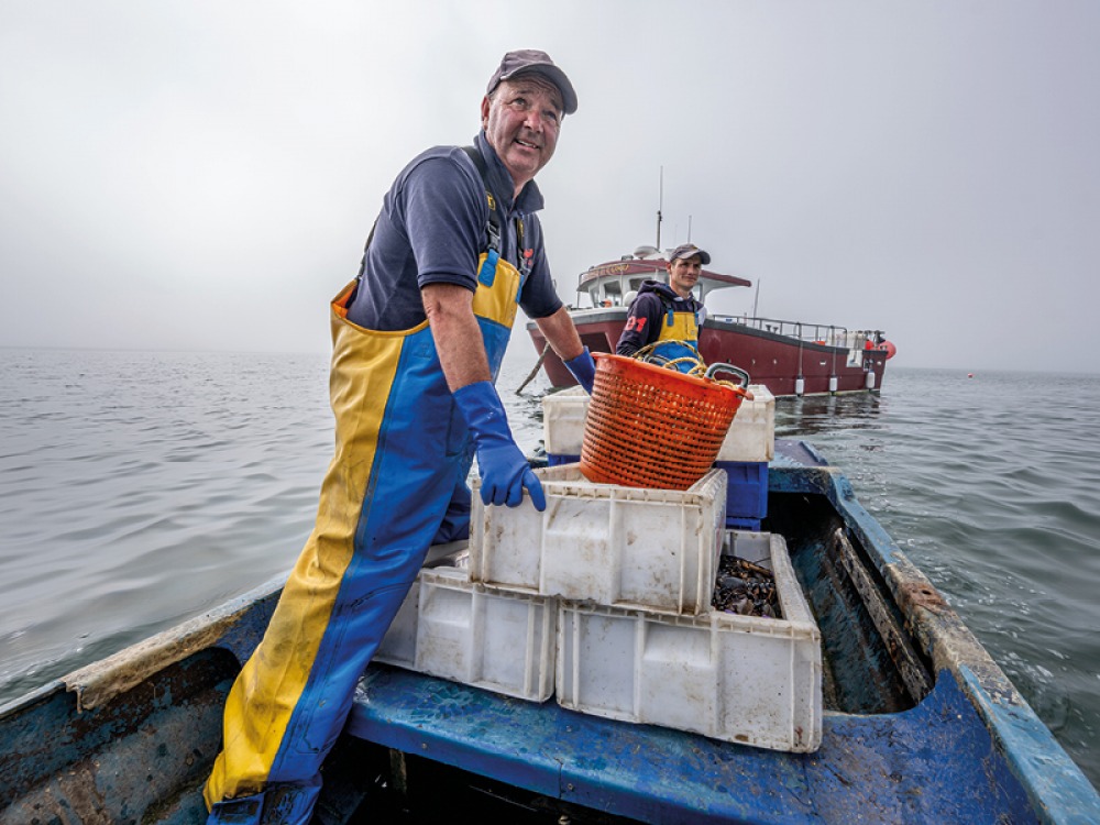 Fishermen on smaller boat transporting catch