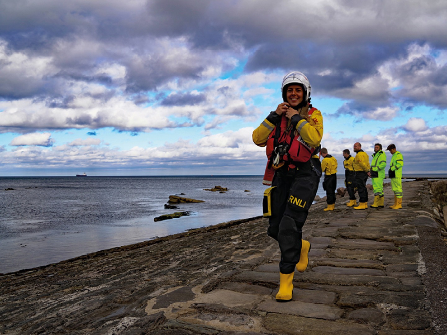 Female RNLI member walking along the coast