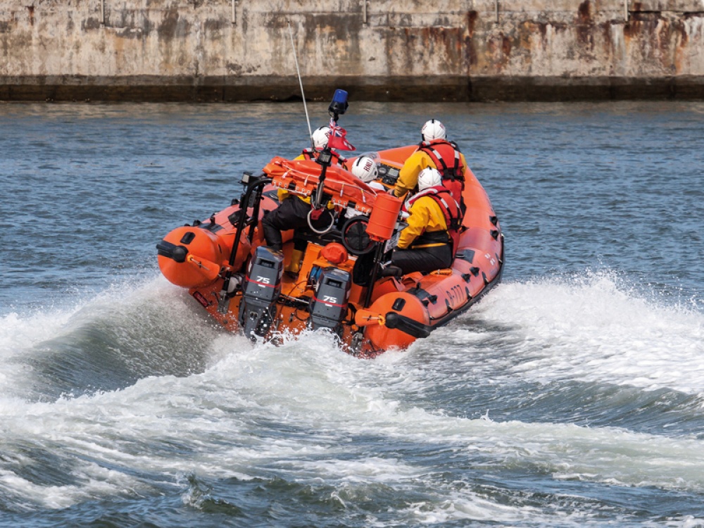 RNLI life boat on choppy water driving away from the camera