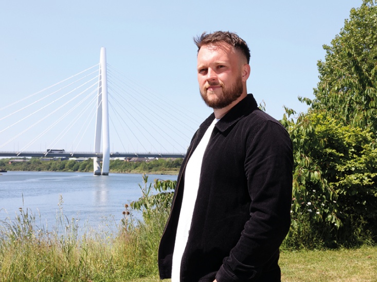 man posing in front of a bridge