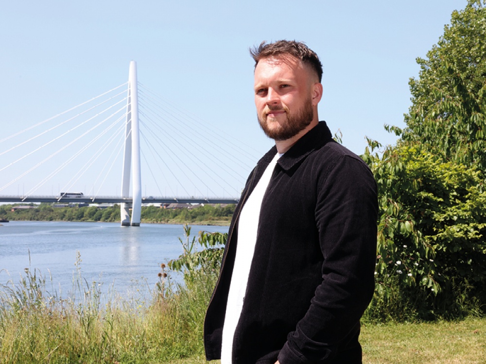 man posing in front of a bridge