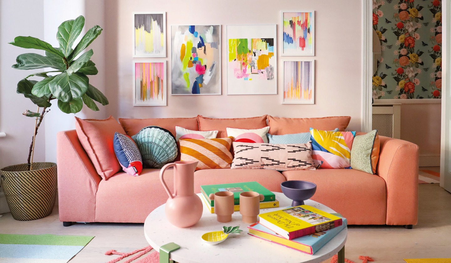 Colourful room with brightly coloured cushions on a pink sofa and Kiraths artwork on the wall