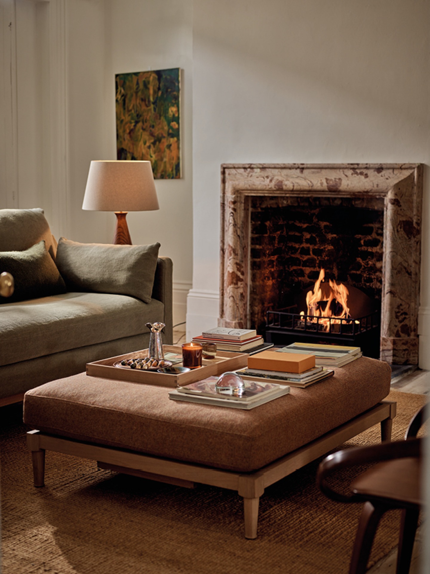 Cosy lounge with Ophelia footstool upholstered in Harris Tweed, open fire and candles
