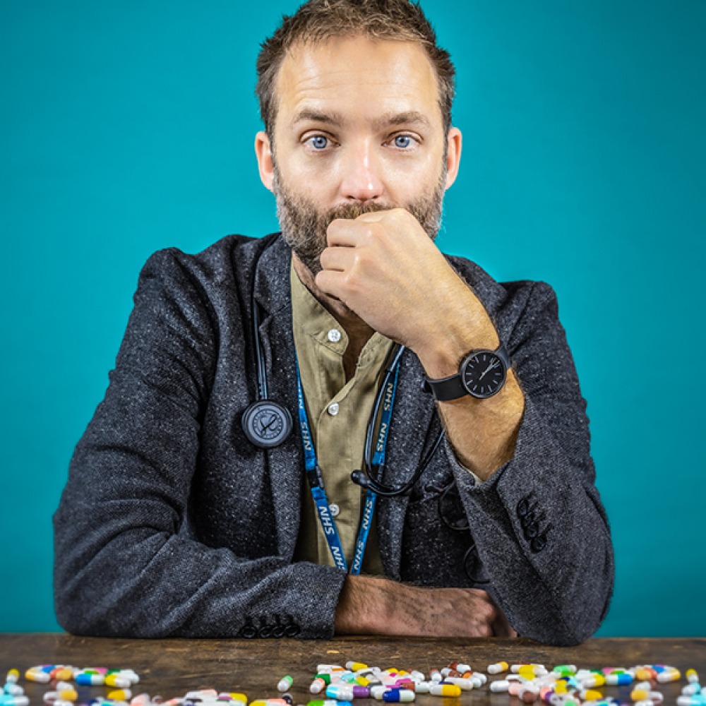 Benji wearing a stethoscope at a table of pills