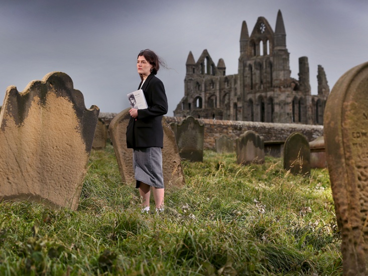 artist stood in a graveyard by an old abbey