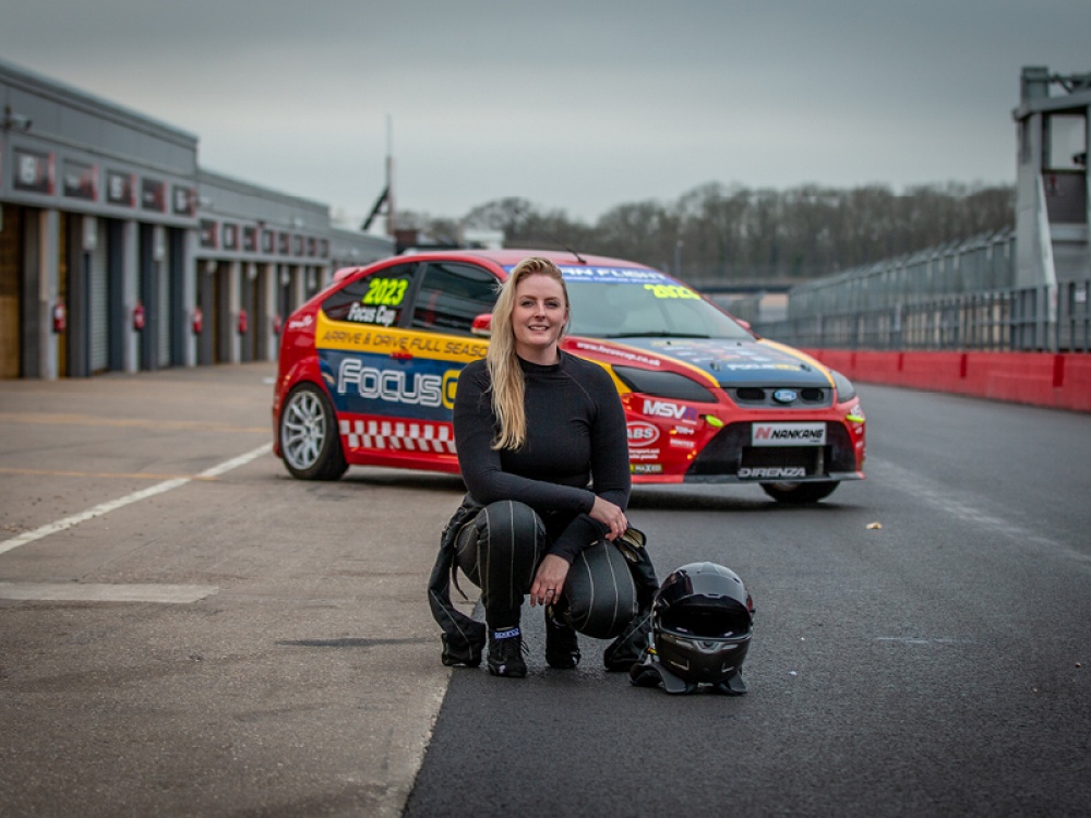 woman crouching down next to a race car