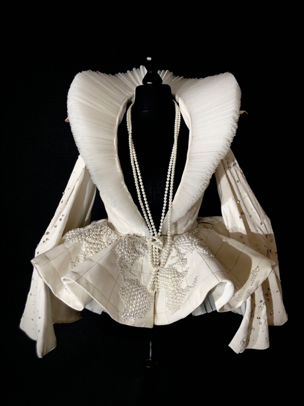 dress making bodice with white fitted jacket with large collar and beads. on Black background