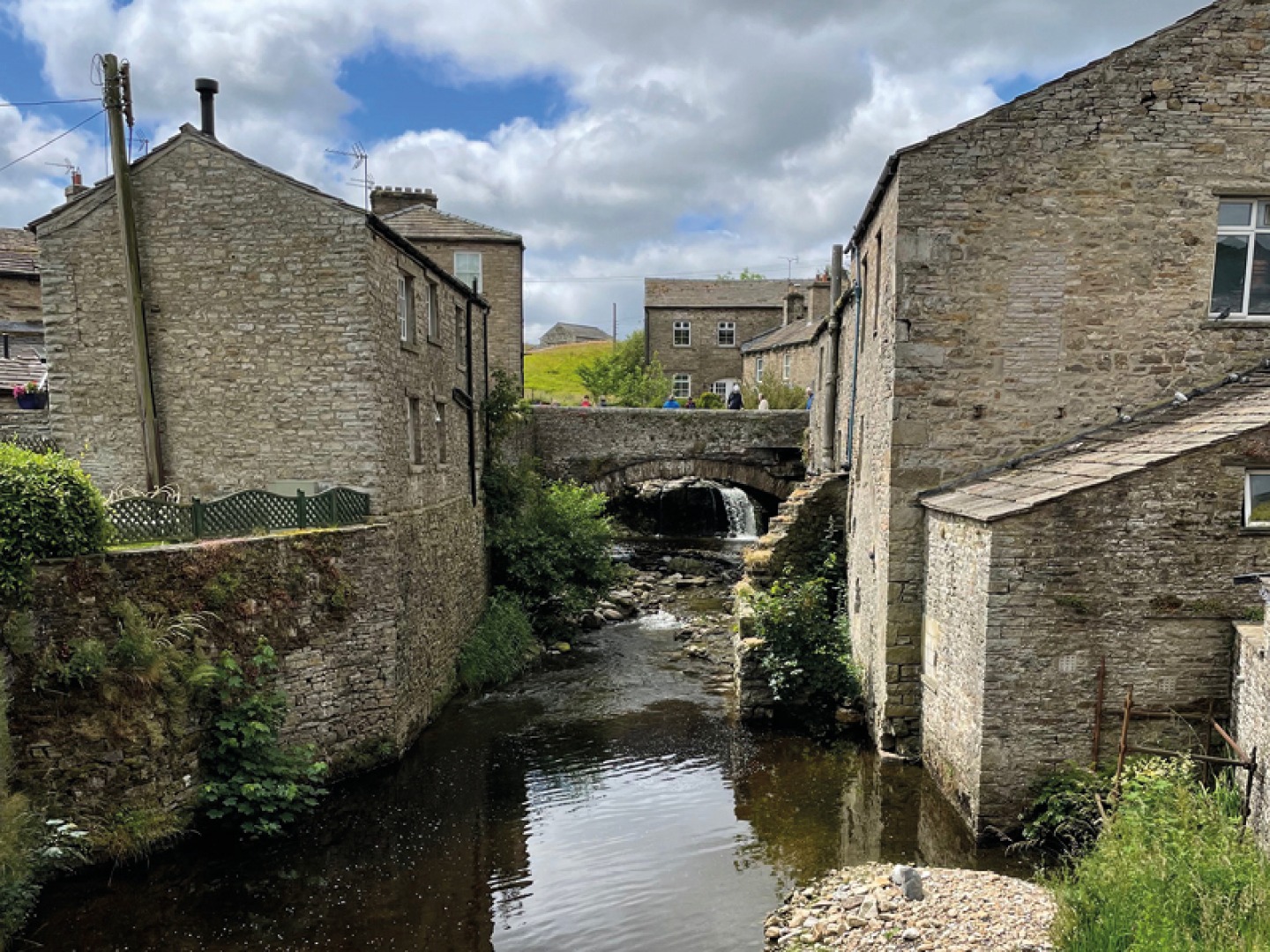 Stone buildings either side of a river with stone bridge