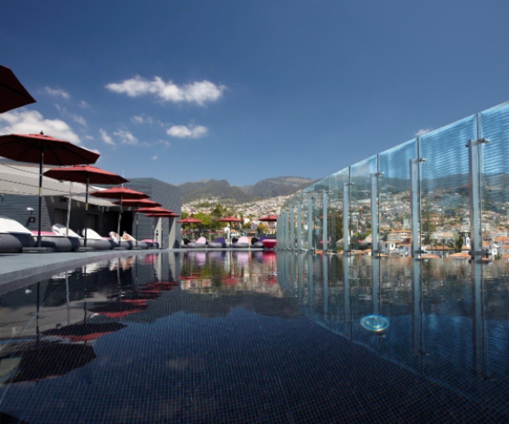 Swimming pool lined with loungers and views over hills