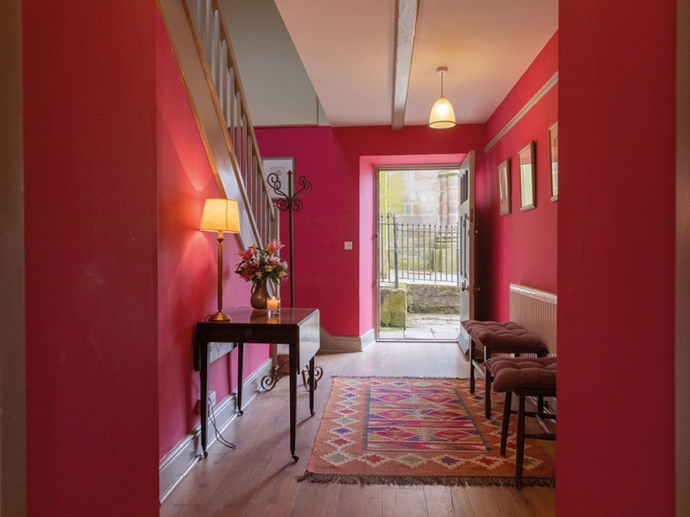 Low lit hall way with red walls and wooden floors