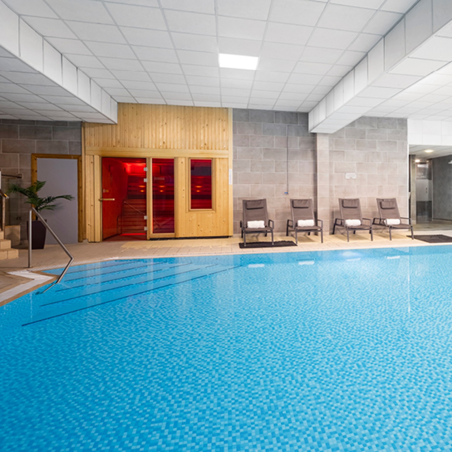 Indoor swimming pool with loungers and a sauna