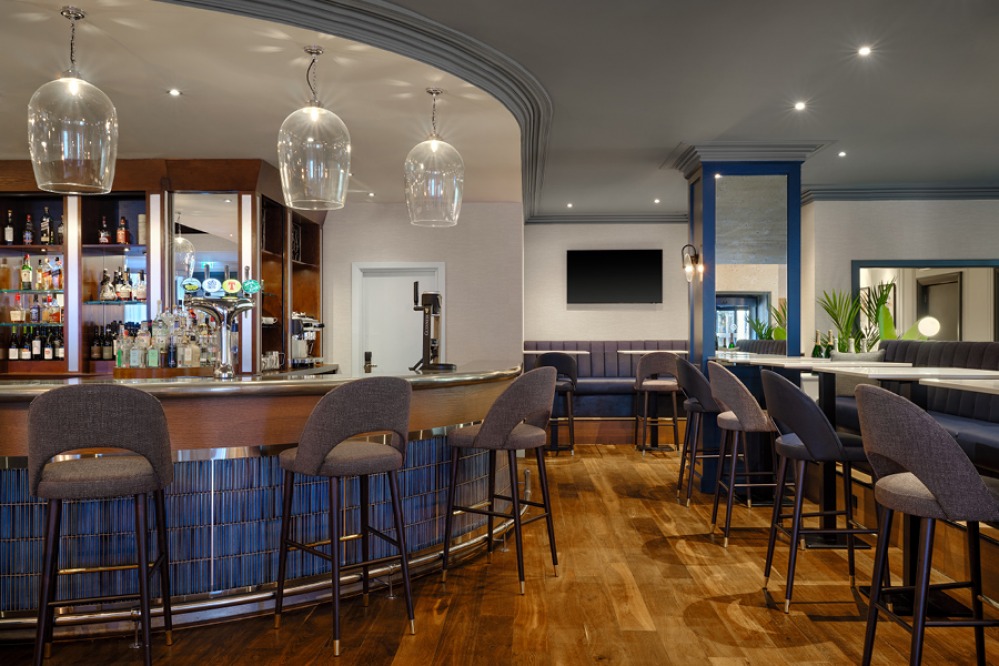 modern blue bar with high marble tables and grey chairs