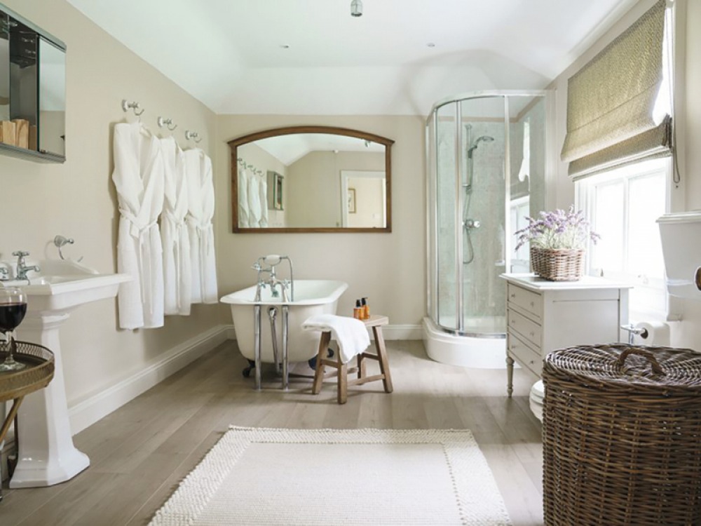 large bright bathroom, with free standing bath, hanging robes and large corner shower