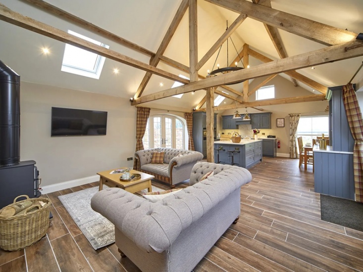 Modern country style open plan kitchen living area. Exposed beams and wood burner