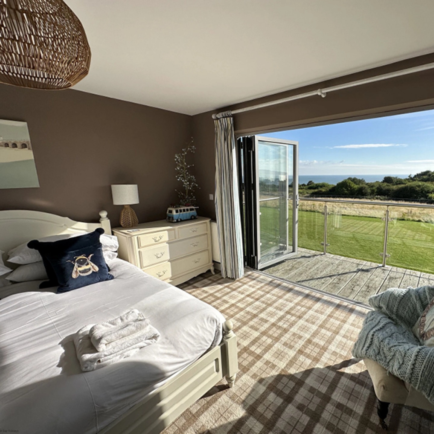Double bedroom with bi-folding door opening onto a balcony with views out to sea
