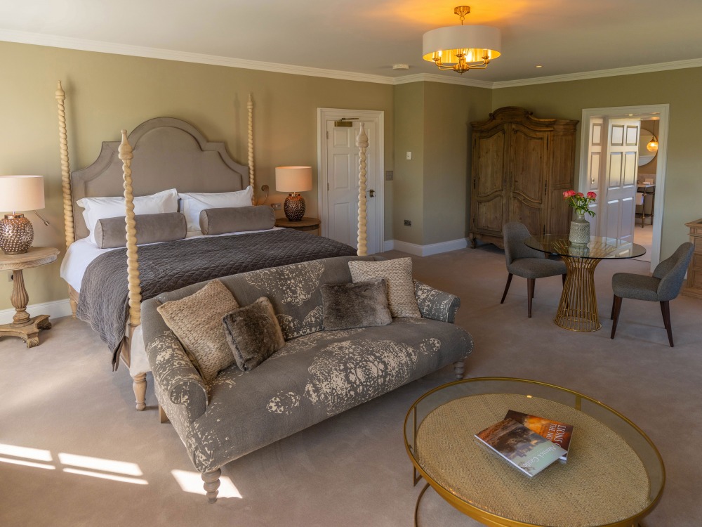 A large bed with an ornate four-poster frame and upholstered headboard, flanked by two matching side tables and lamps