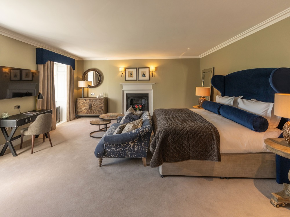 Large double guest room with lounge chair and desk