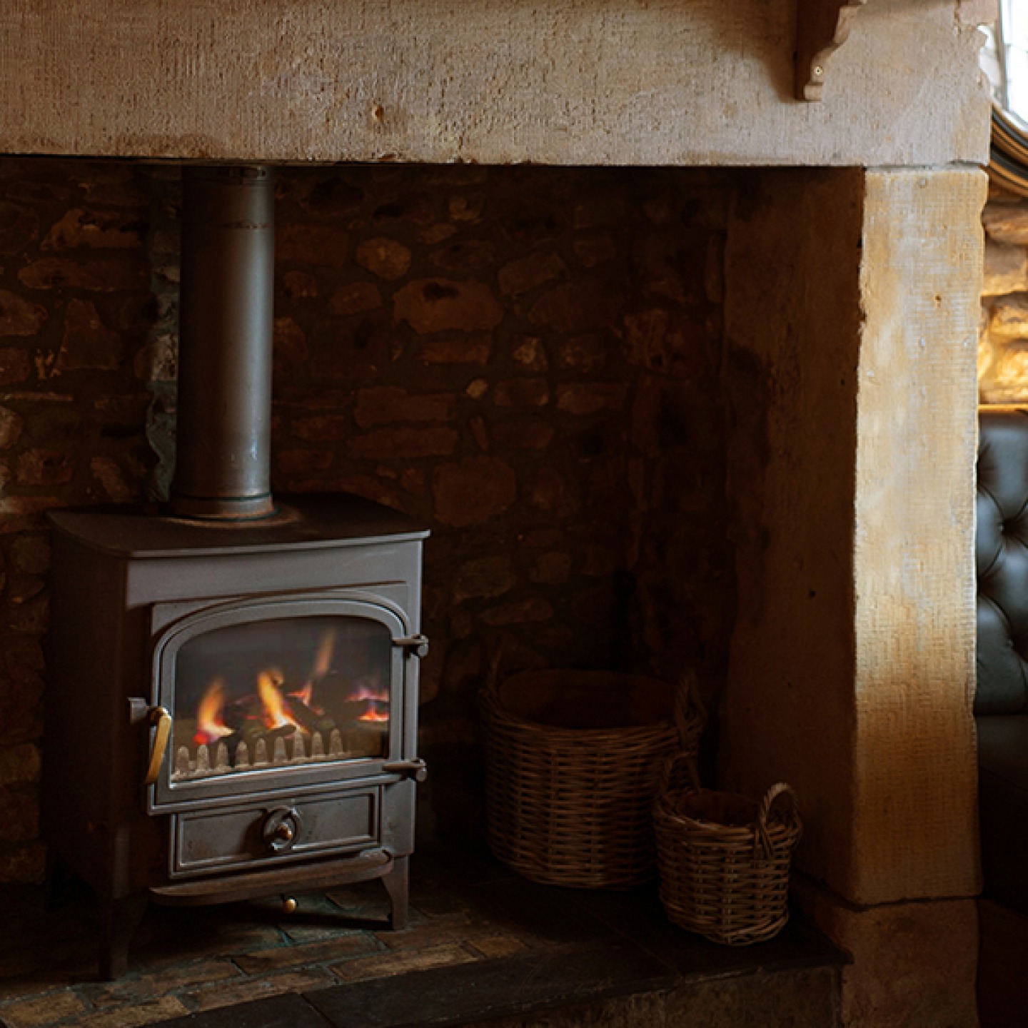 wood burner in a large stone fireplace with wicker baskets