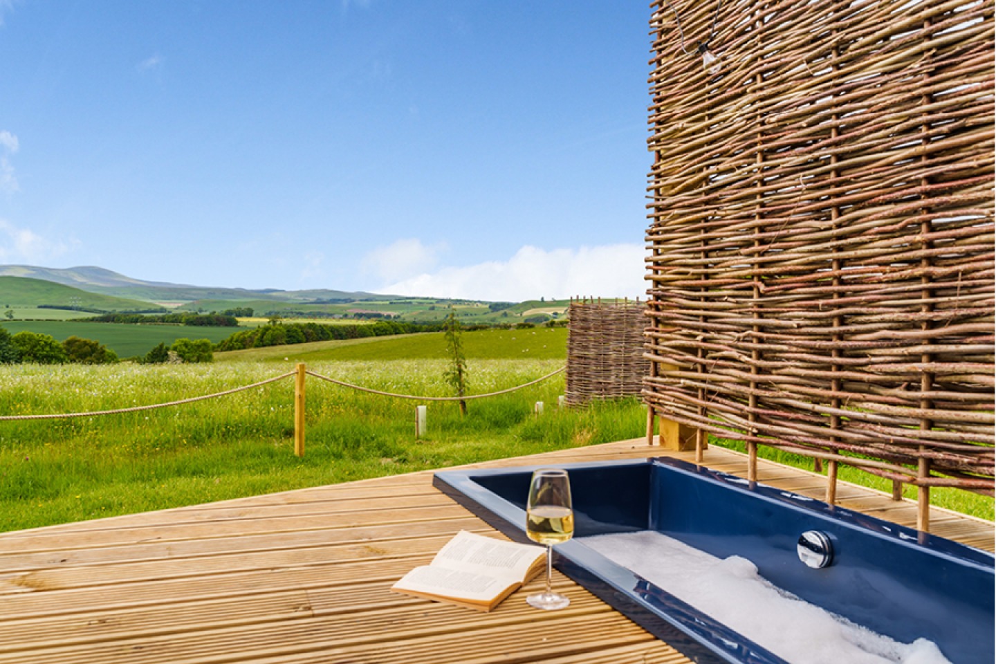 Outdoor bathtub sunken into a deck overlooking fields