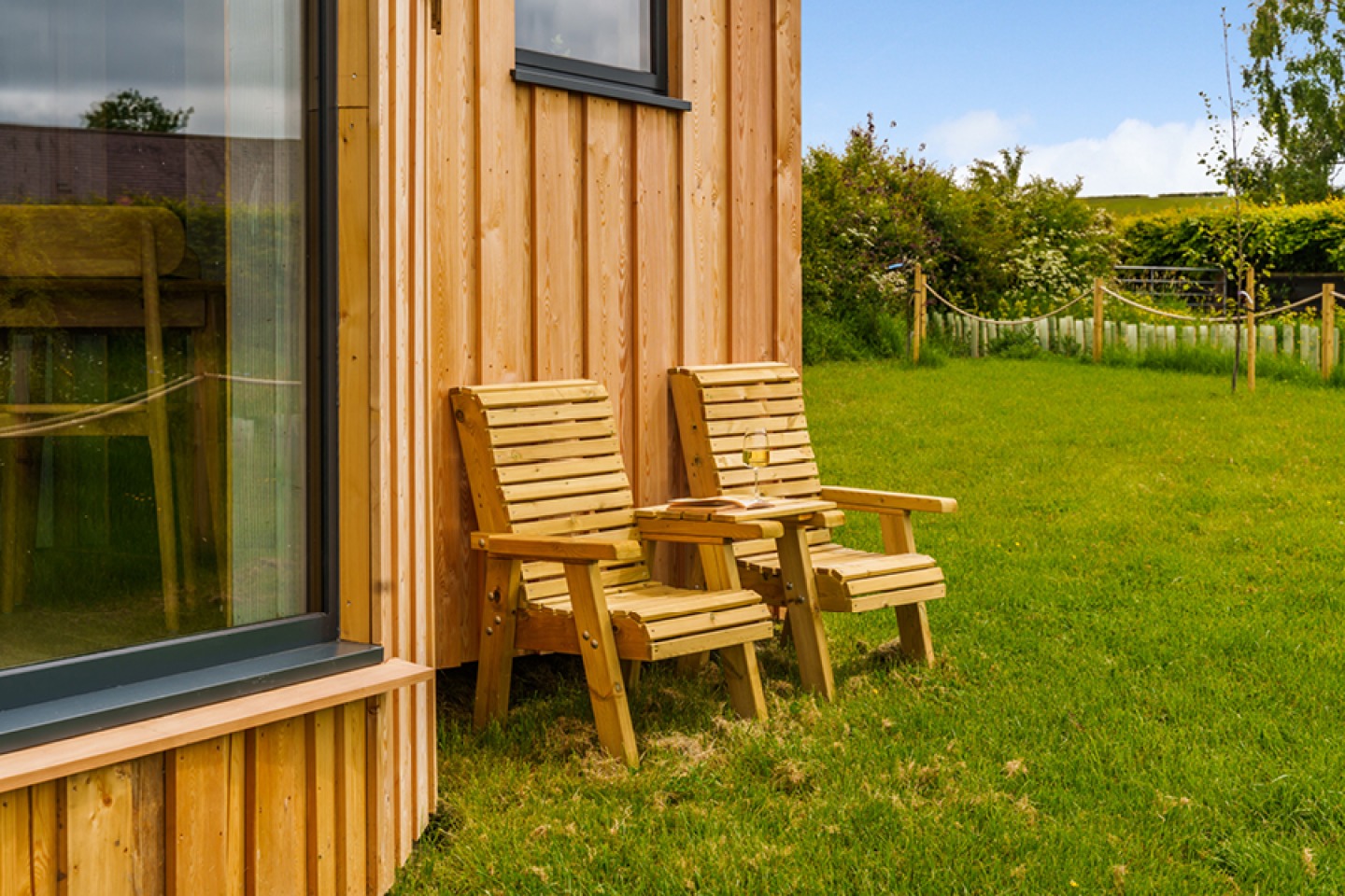 Two wooden chairs outside a wooden glamping pod
