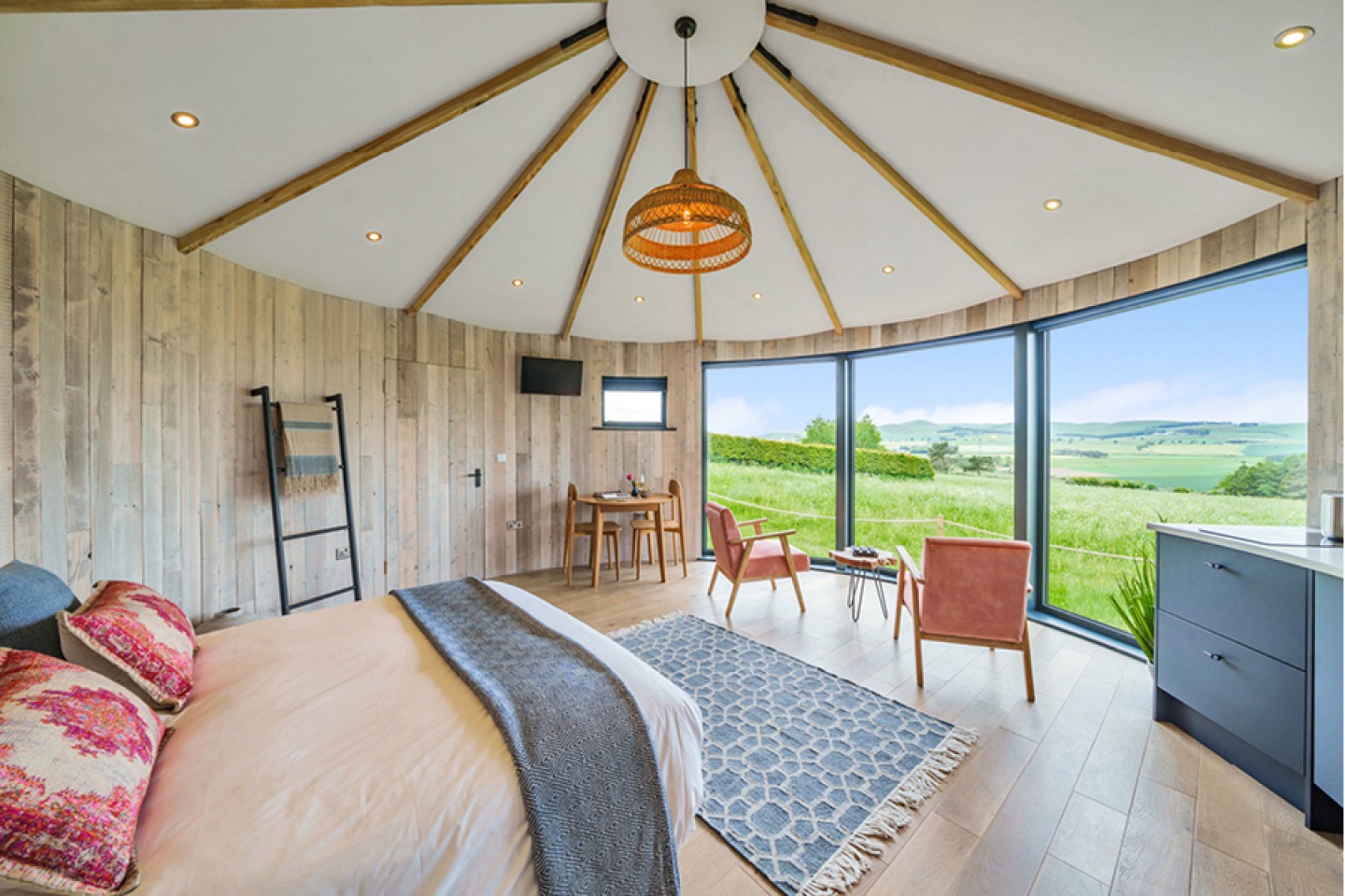 Sacni-inspired interior of a round glamping pod with large floor to ceiling windows