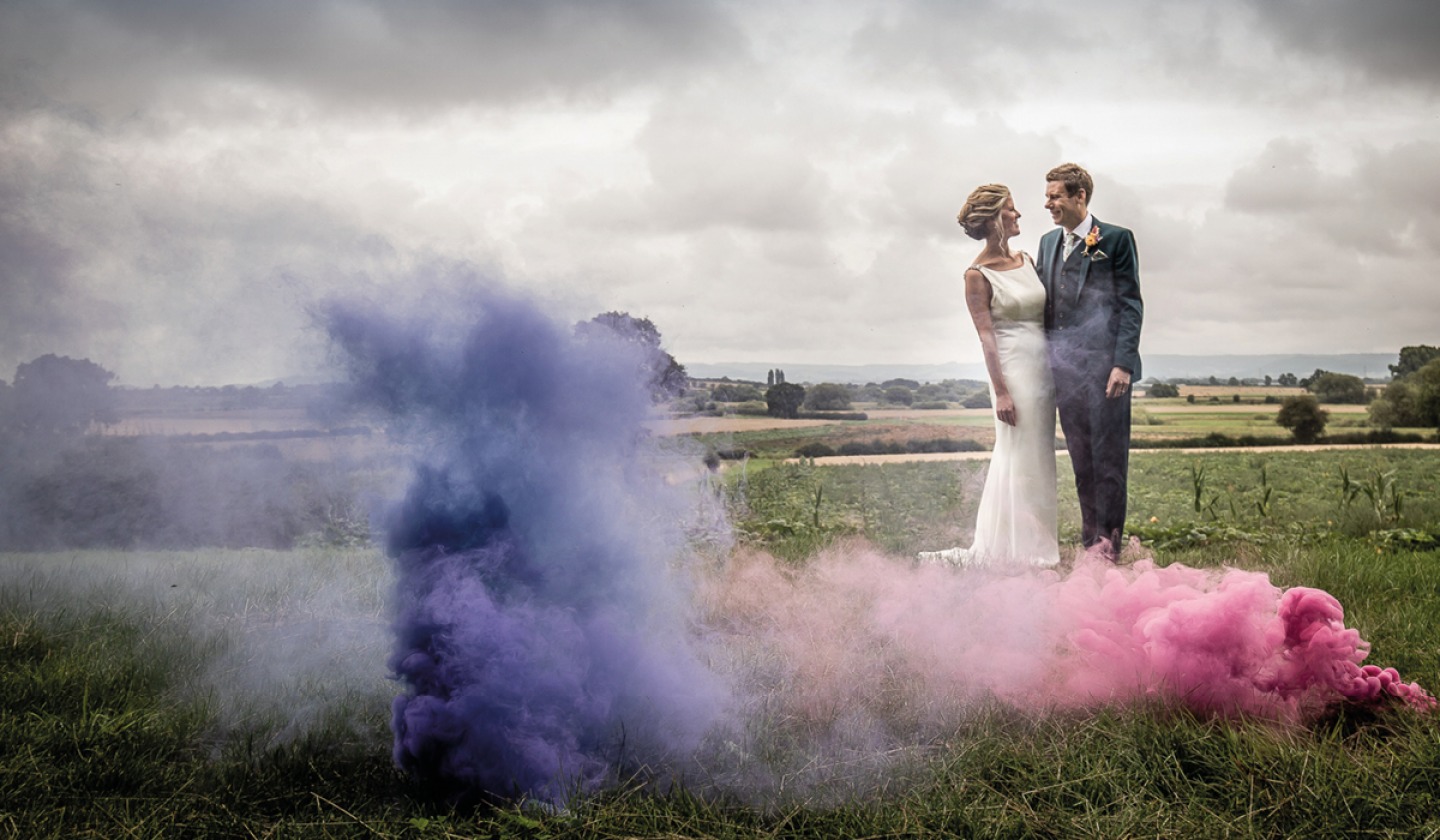 Bride and groom behind a colourful smoke