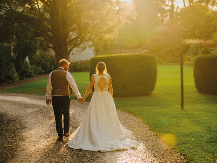 newly married couple walking down a gravel road in sunset