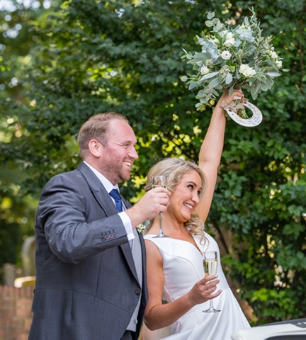 bride and groom with glass of fizz