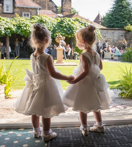 flower girls looking out over lawn holding hands
