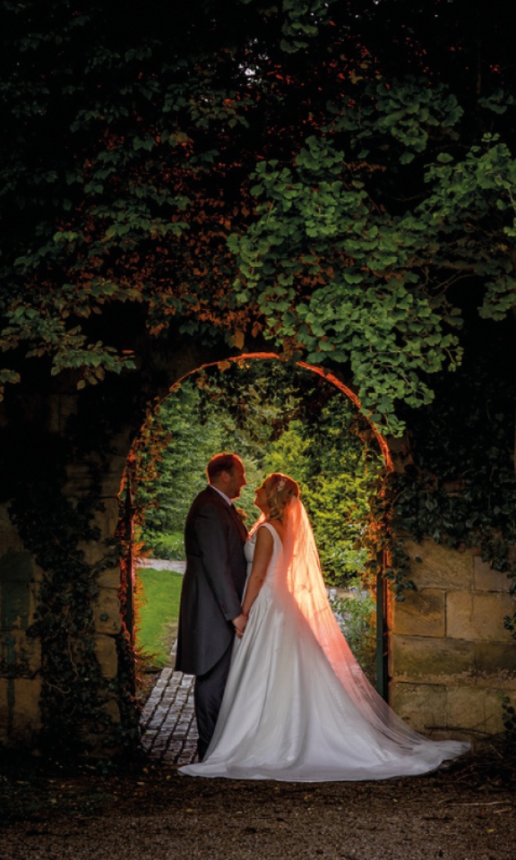 bride and groom posing under archway