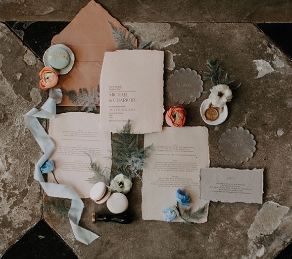 Ariel view wedding stationery laid out with ribbons flowers and macaroons