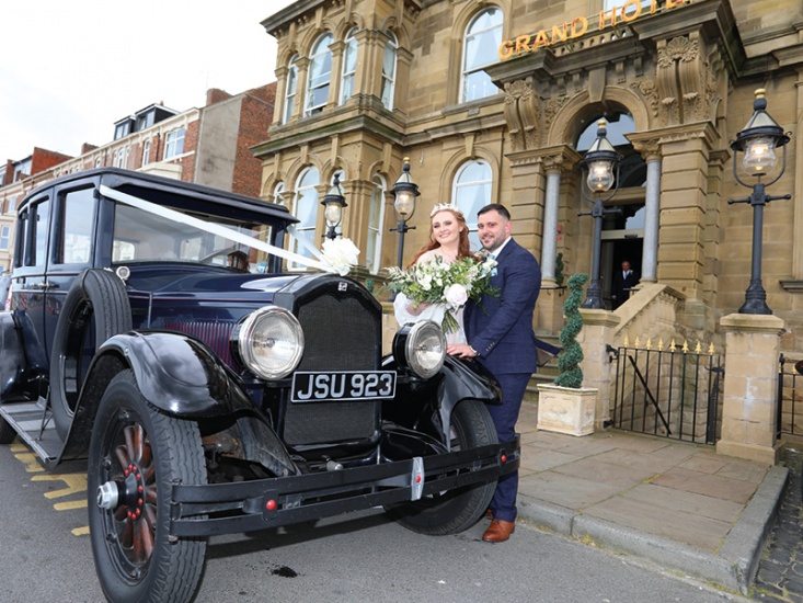 Kate and Ryan beside the wedding car