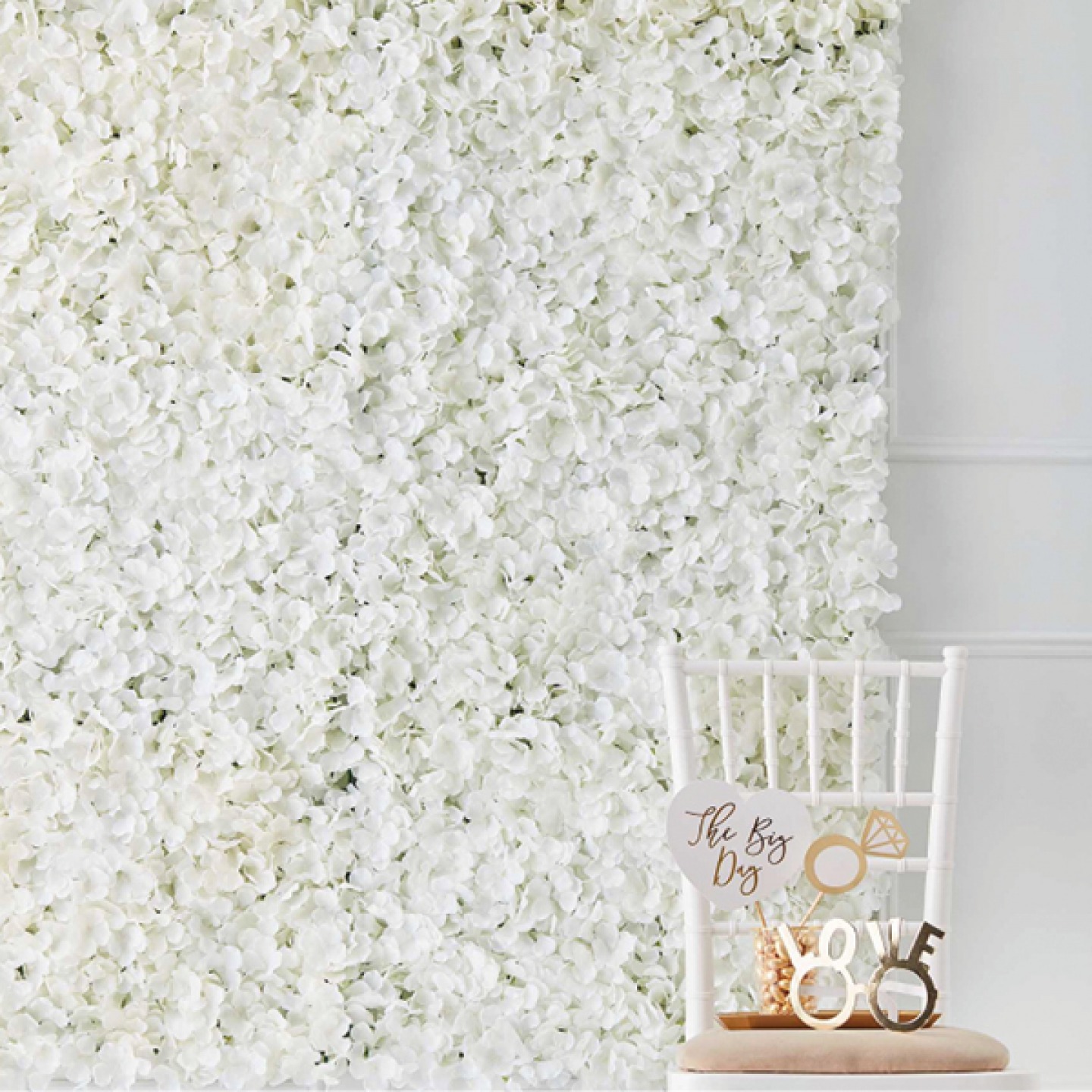 floral back drop with white chair and Photo Booth props