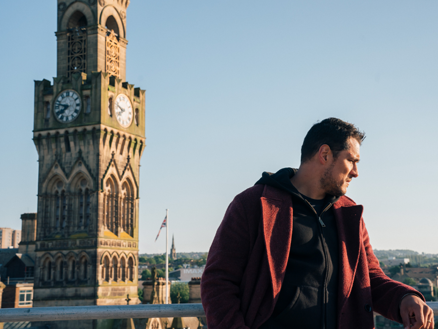 man in red jacket stood looking over Bradford clock tower