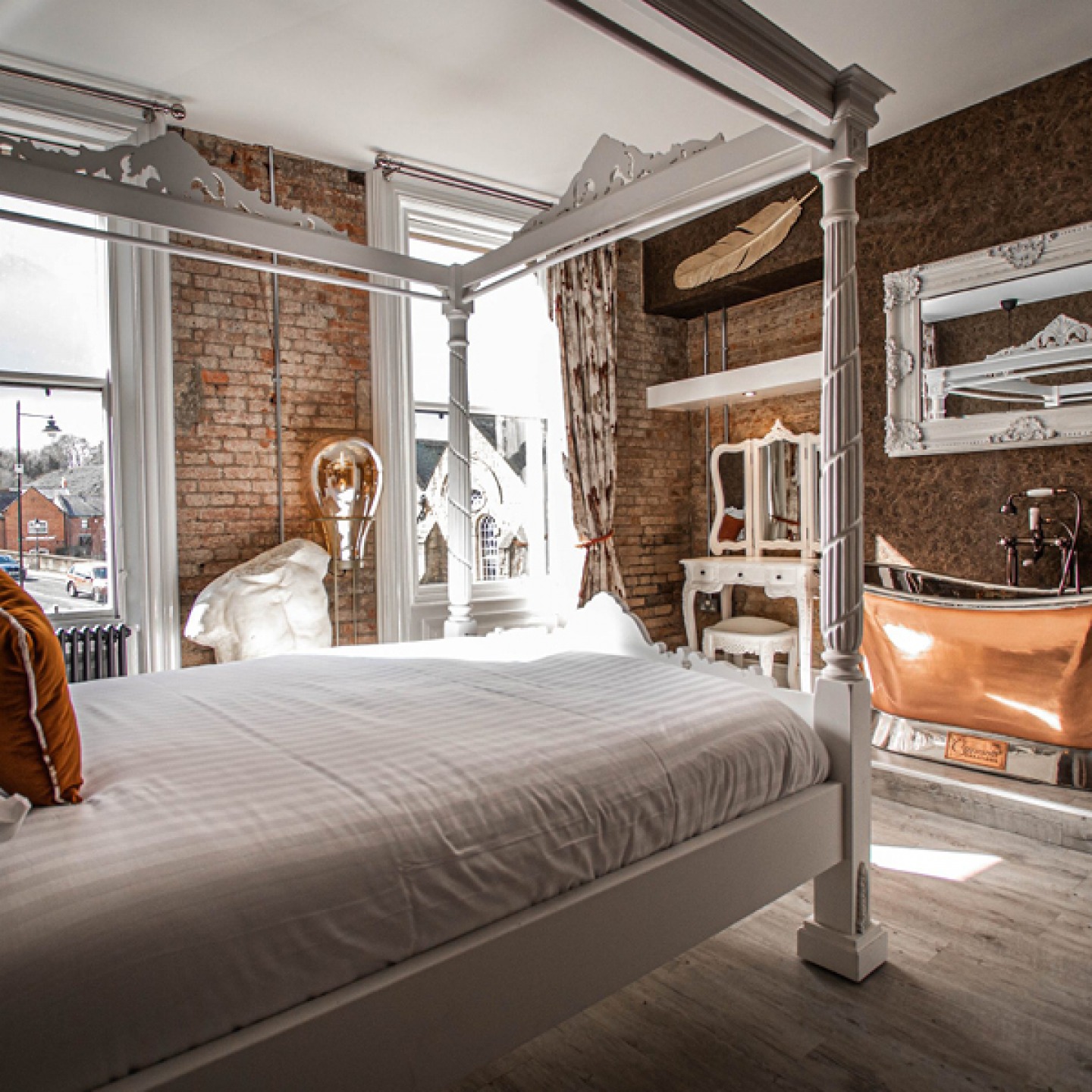 bedroom at The Auction Housewith four poster bed, copper free standing bath and exposed brick walls