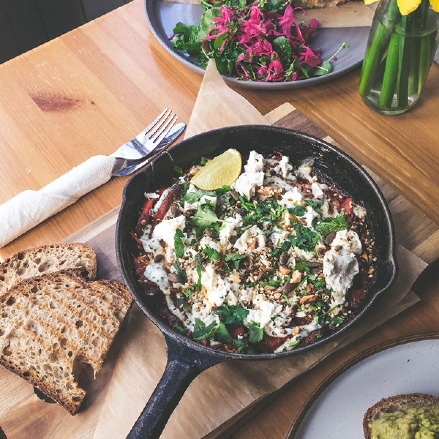 food in a cast iron pan served with bread on a wooden board
