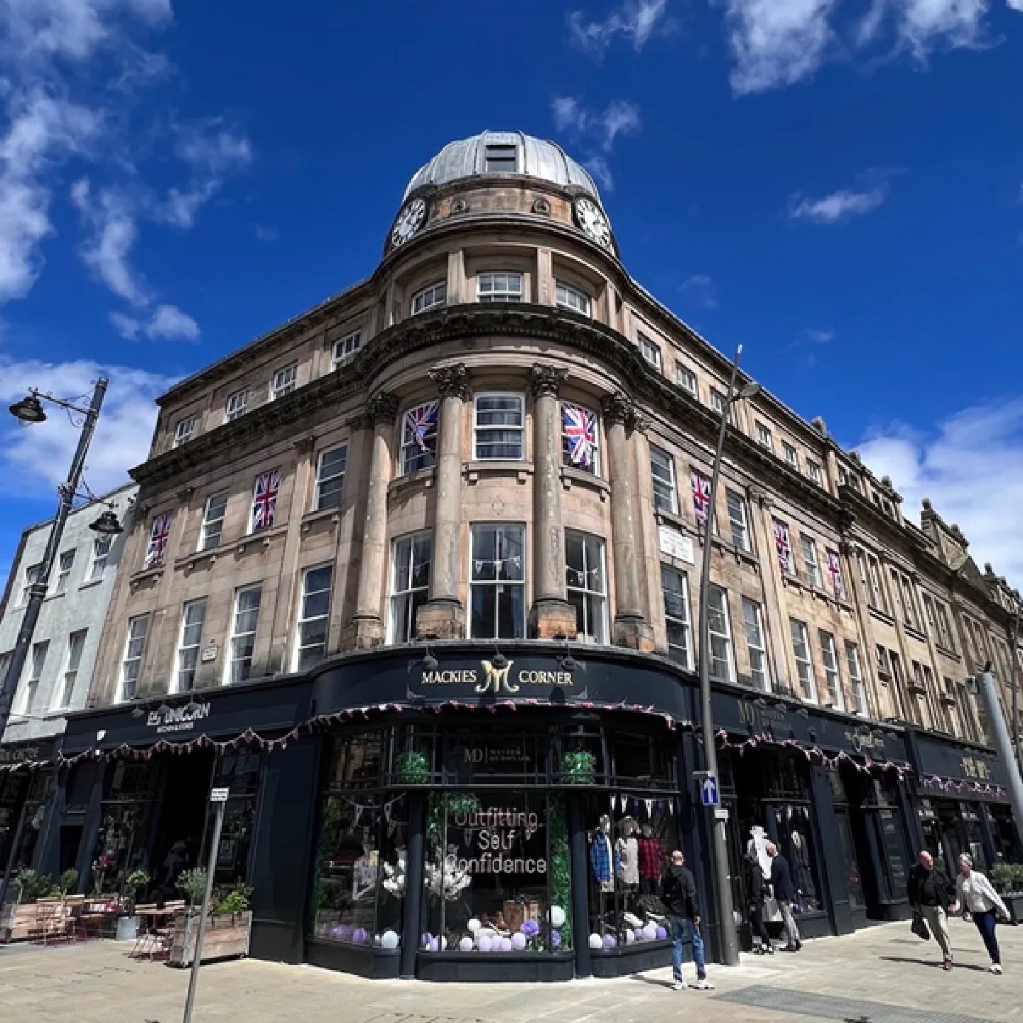Large stone building with black shop front at the bottom