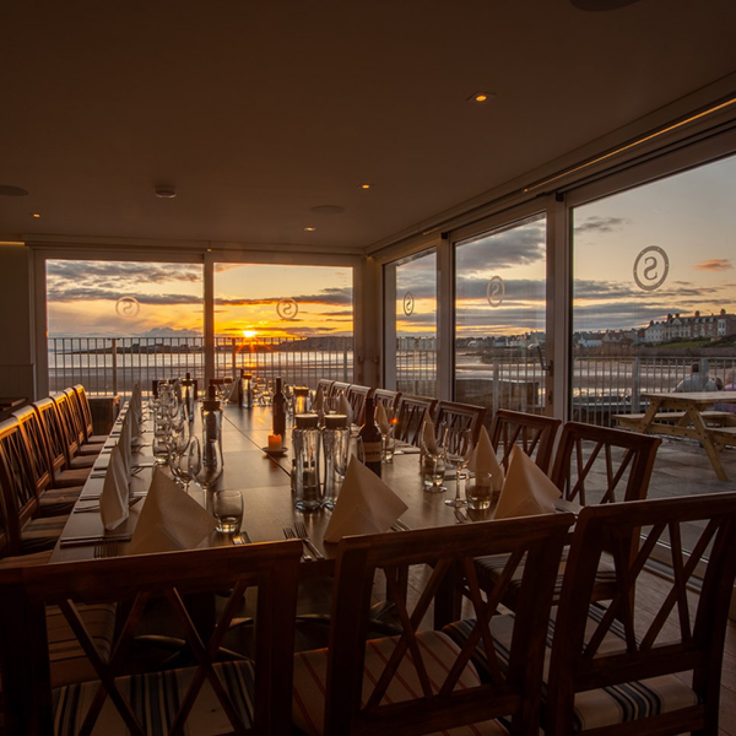 large table looking out glass door to the beach and sea