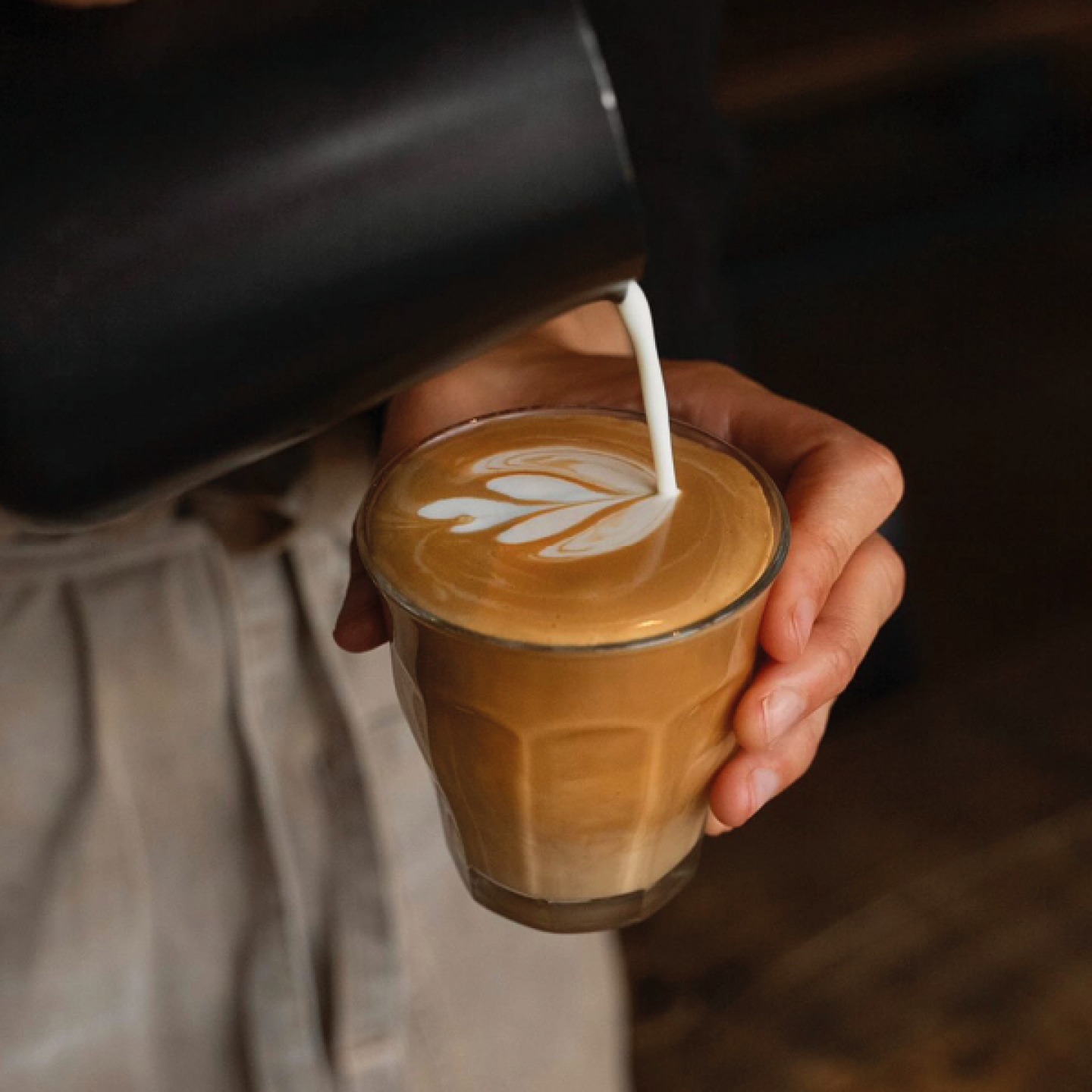 Barista making a coffee in a glass cup at Woods Coffee