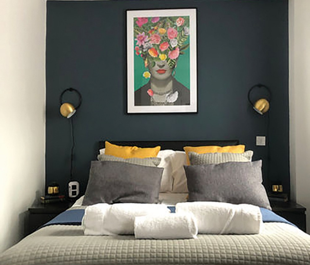 Modern guest room with a dark feature Wall, floral print above the bed and wall lights