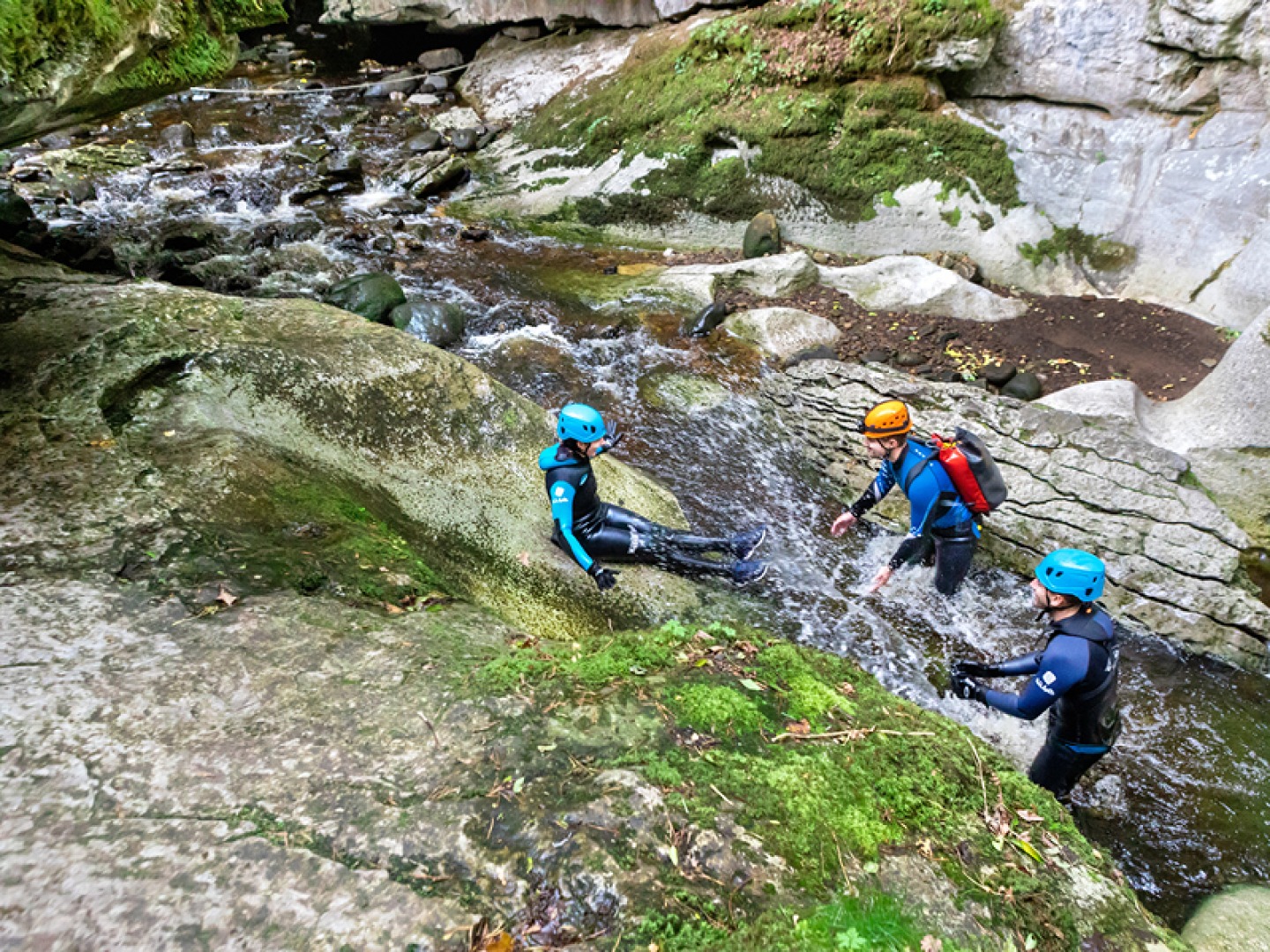 3 people sliding down rocks as an extreme sport
