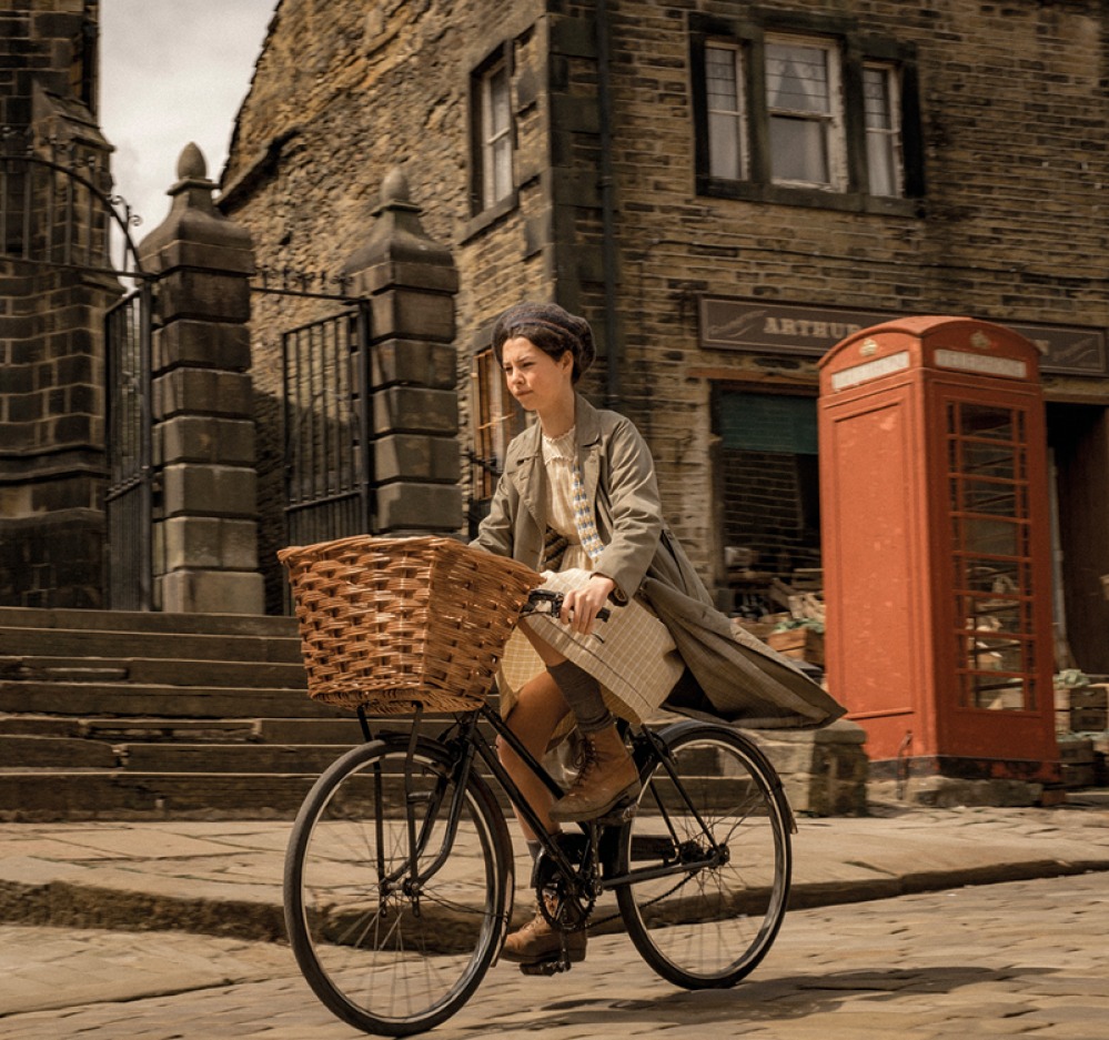 girl riding a bicycle with a basket down a street