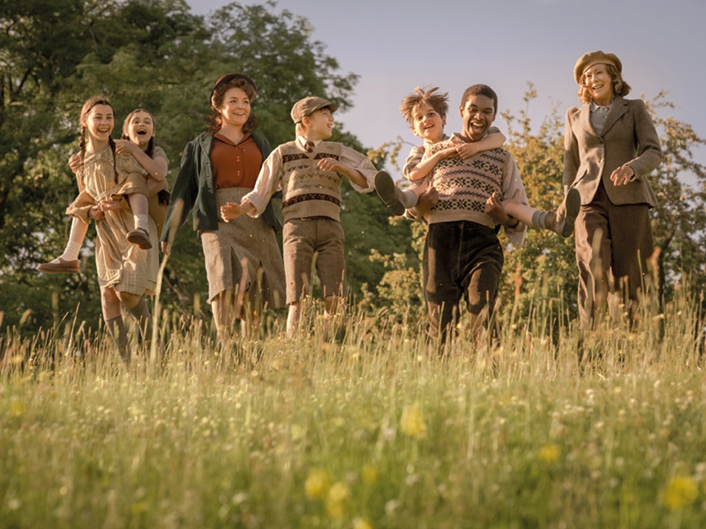 cast in costume walking through field of long grass
