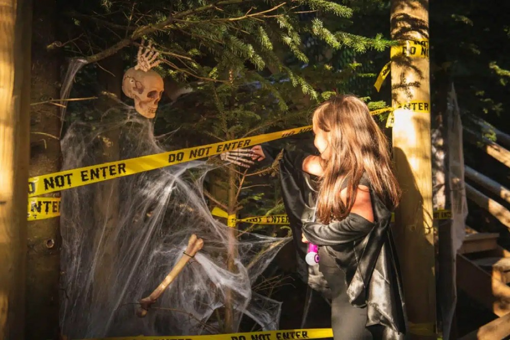 Young girls dressed as a witch looking at a Skeleton covered in web with do not enter signs