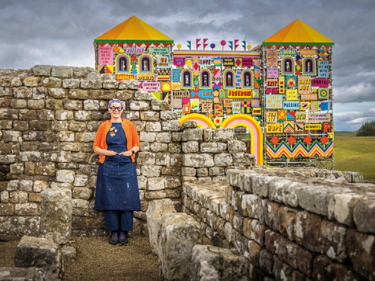 Morag Myerscough standing to the front of the Art Installation of Housesteads