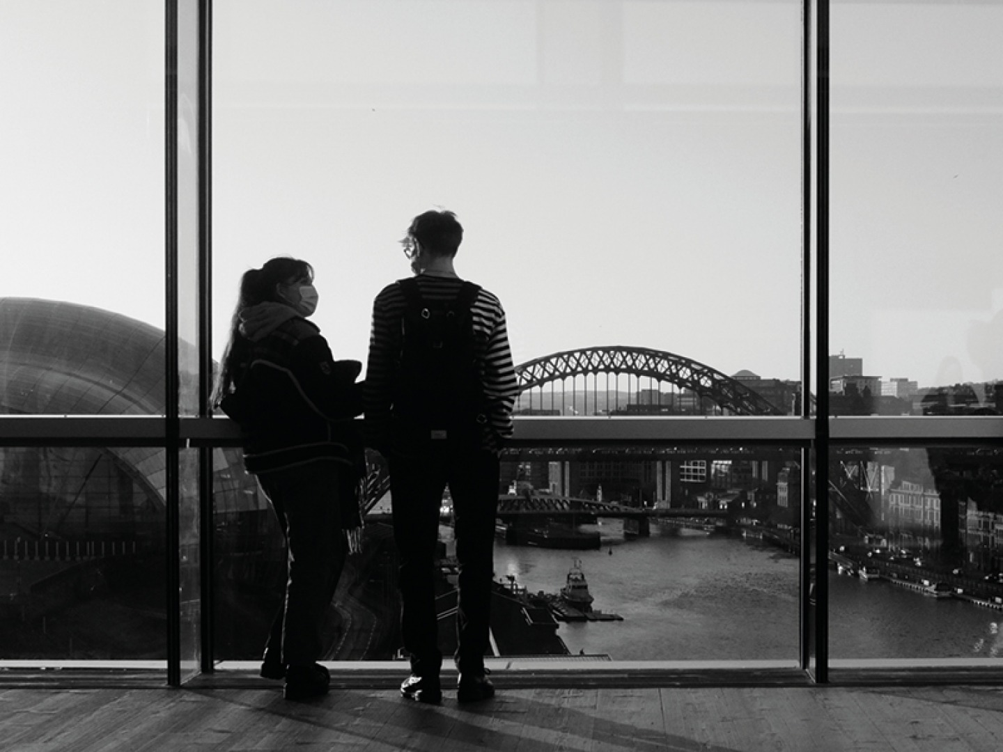 Two people looking at one another with views of Newcastle quayside in the background