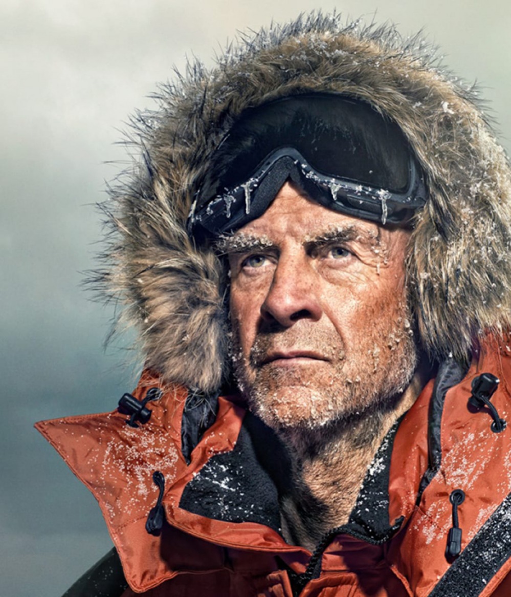 SIR RANULPH FIENNES wearing fur hooded coat and goggles covered in frost and ice