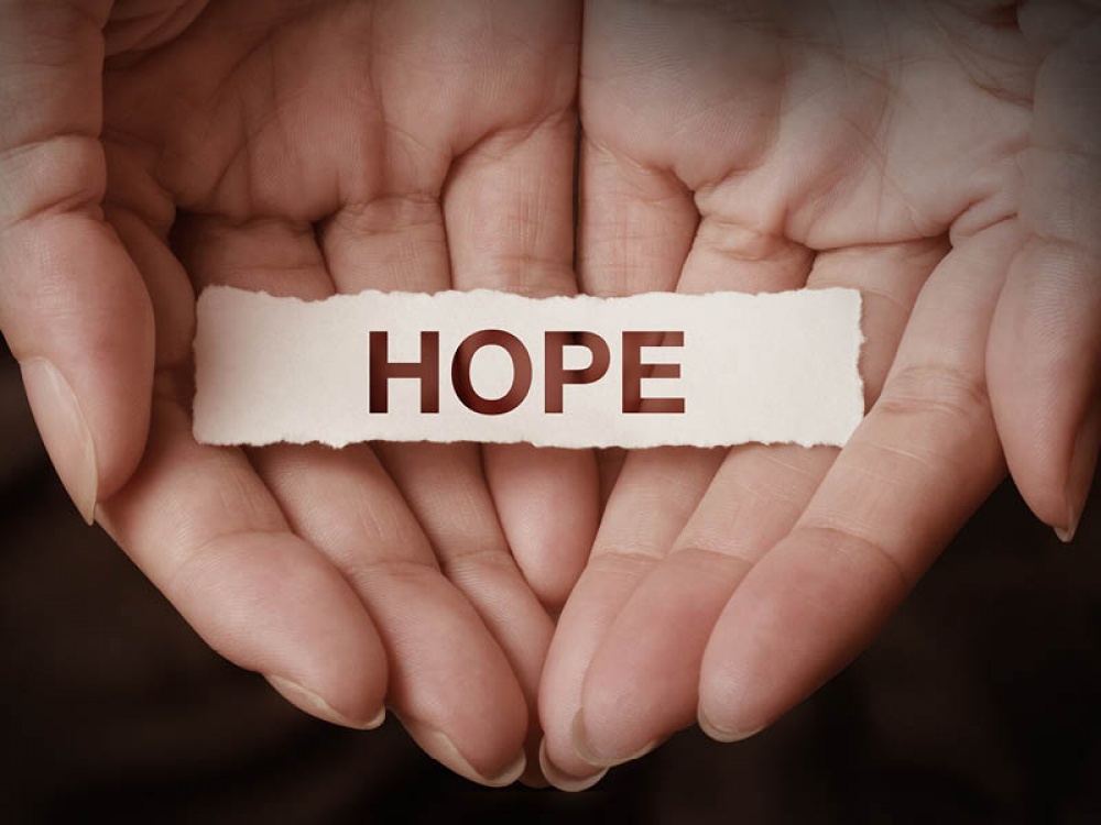 hands holding paper spelling hope
