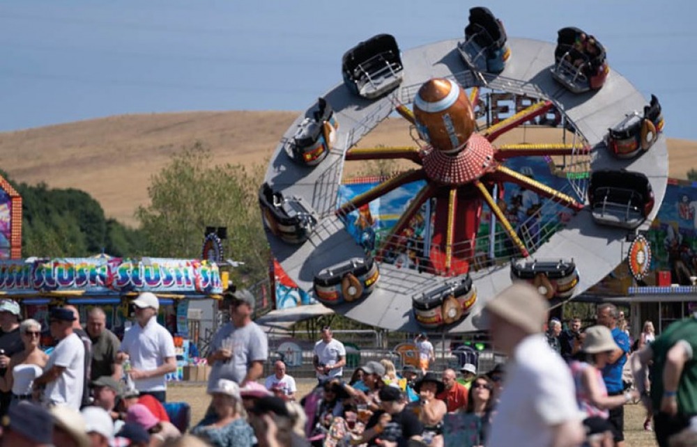 fairground rides with people sitting in chairs watching a performance