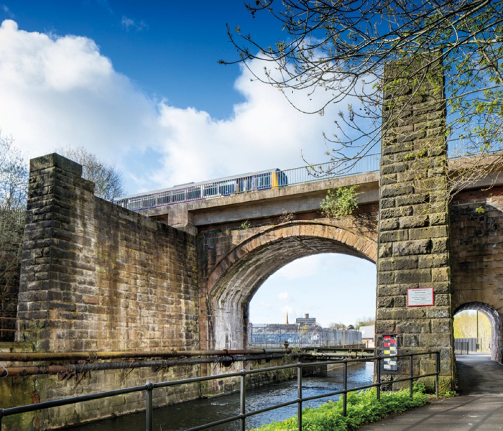 Skerne Railway Bridge, Darlington. General view of the north side of the railway bridge from the north-east, with a train passing over it. © Historic England Archive